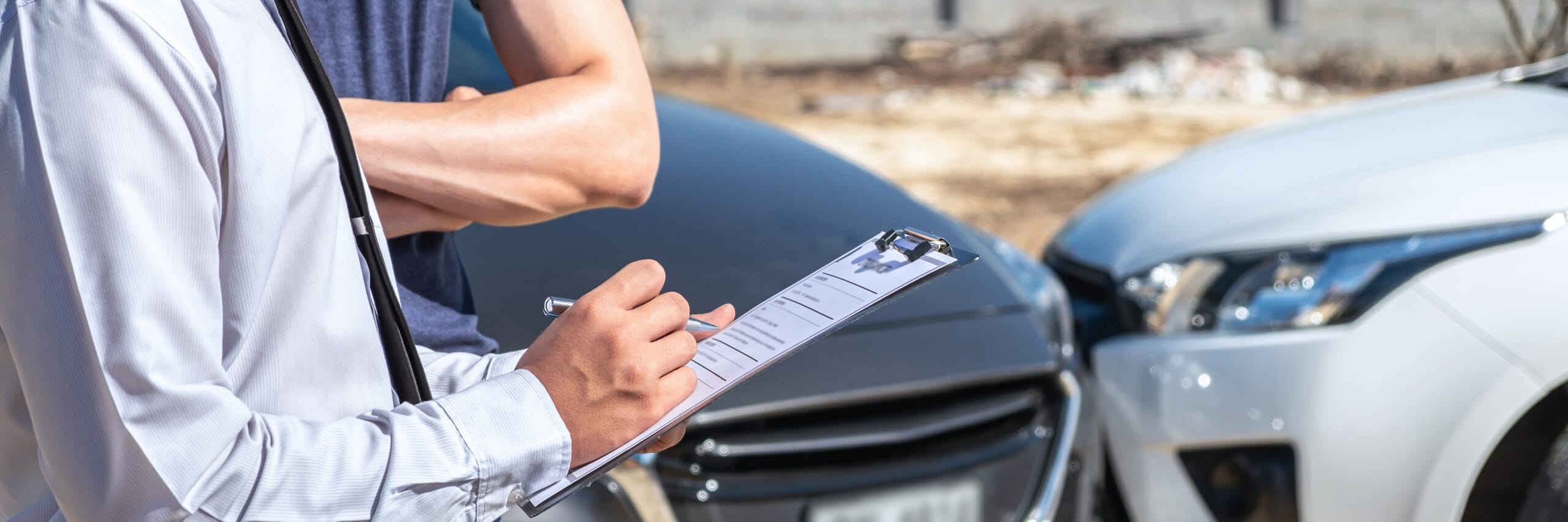 Adjuster inspecting two damaged vehicles.