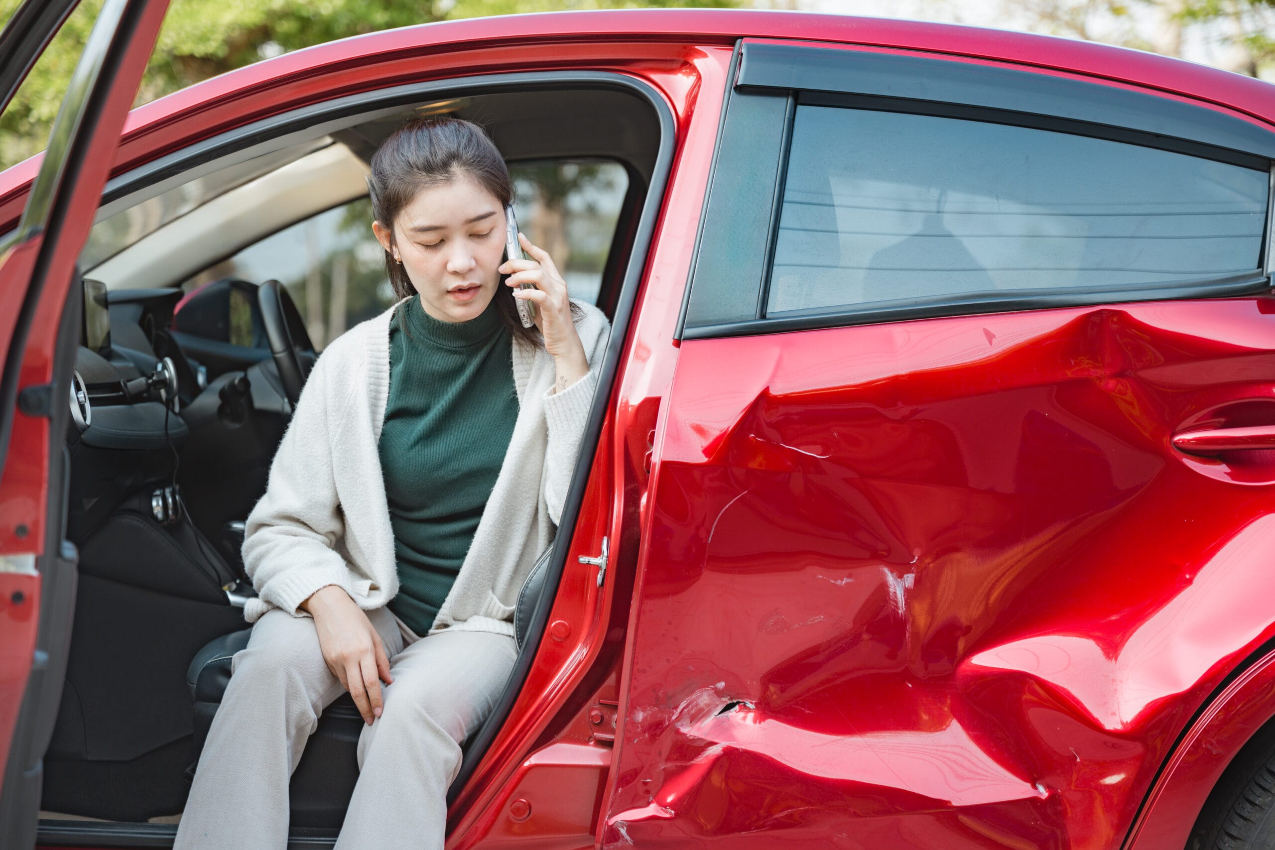 Woman on phone by damaged car
