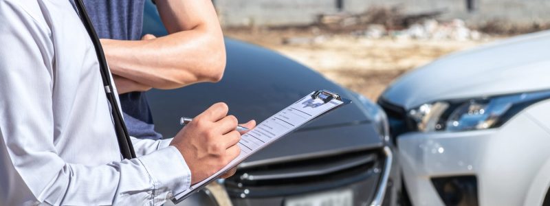 Adjuster inspecting two damaged vehicles.