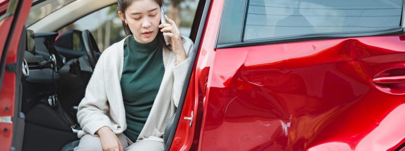 Woman on phone by damaged car